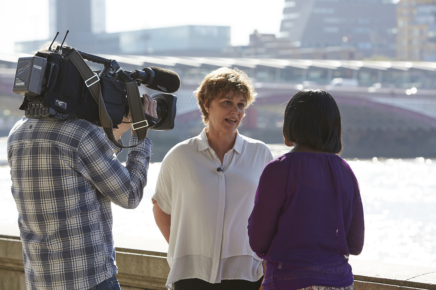 Artichoke's Director, Helen Marriage wearing a white shirt and being interviewed on camera by a woman with dark hair in a purple top