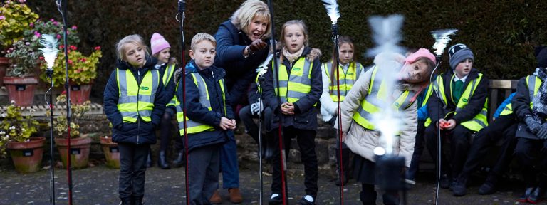 Group of school children with teacher wearing yellow hi vis jackets.