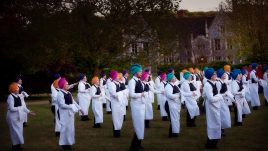 Waiters in multicoloured turbans and black and white uniforms standing in a group in a garden