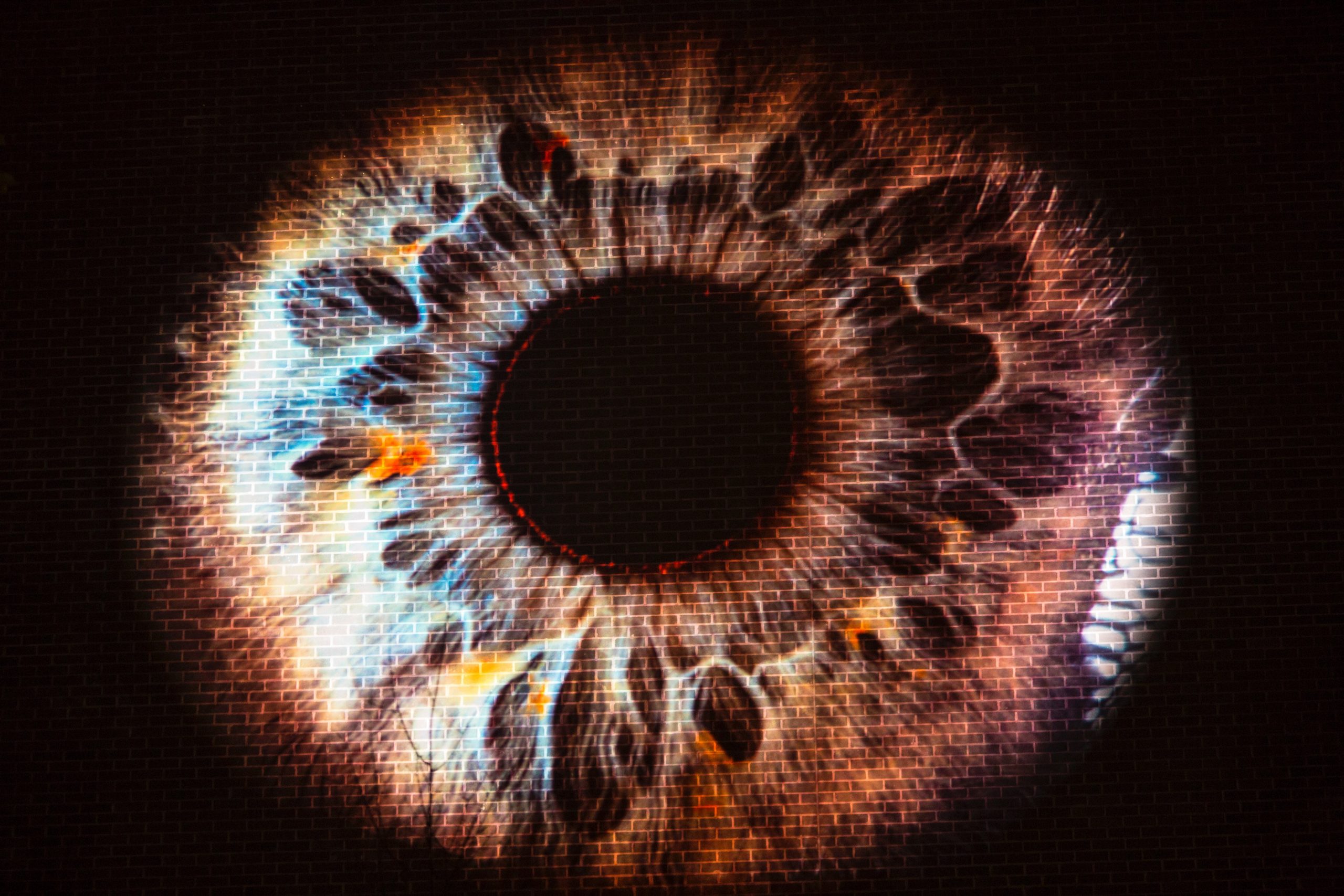 Image of a brown eye projected onto a brick wall