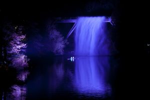Illuminated purple waterfall with canoes underneath