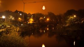 A large scale lighbulb suspended over a river