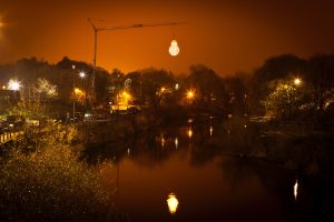 A large scale lighbulb suspended over a river