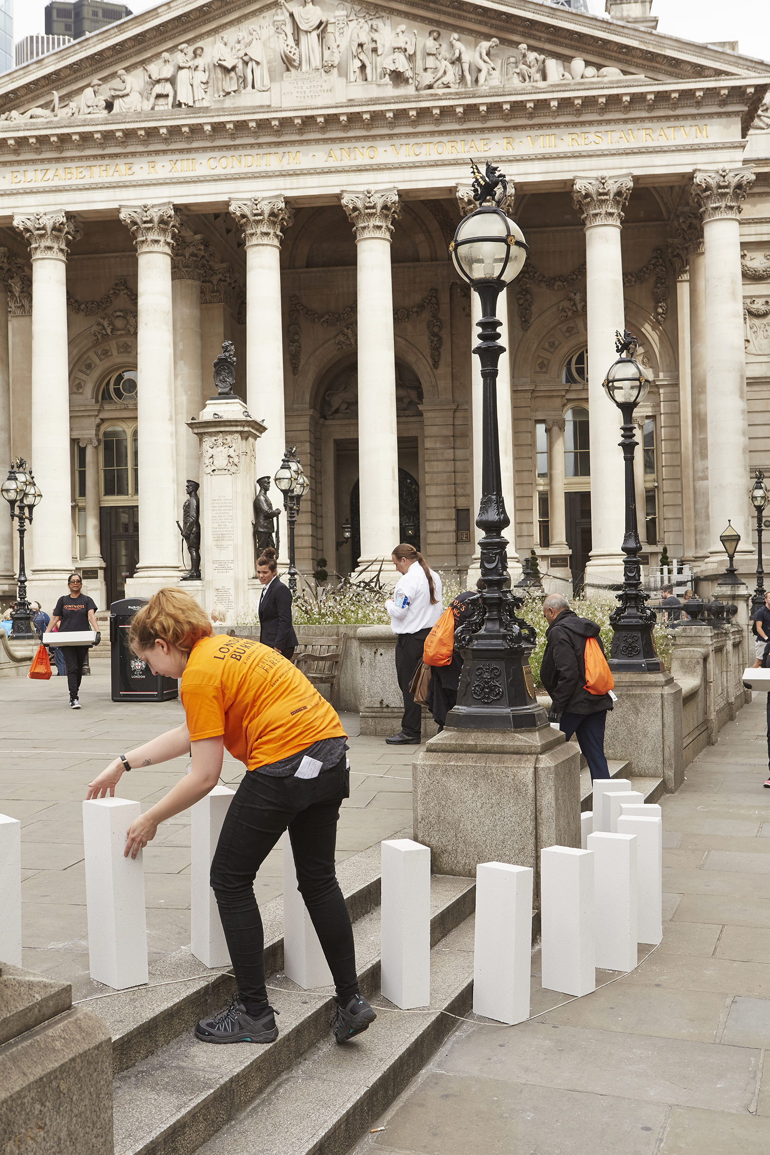 A volunteers arranging breezeblocks into a row like dominoes