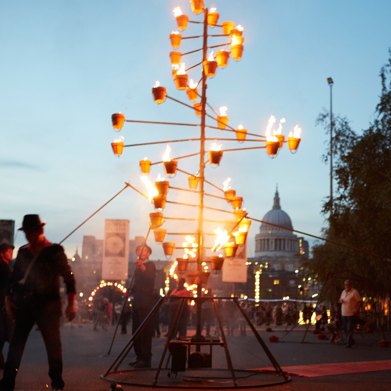 a Helix shaped structure with a small pot lit up into a flame at each end of the helix form