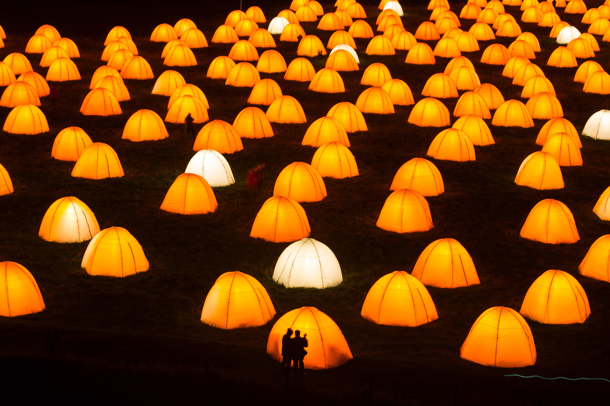 Peace Camp at Dunstanburgh Castle. Two silhouettes of people in front of one of the tents