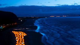 Aerial shot of peace camp tents glowing at dusk by the seafront