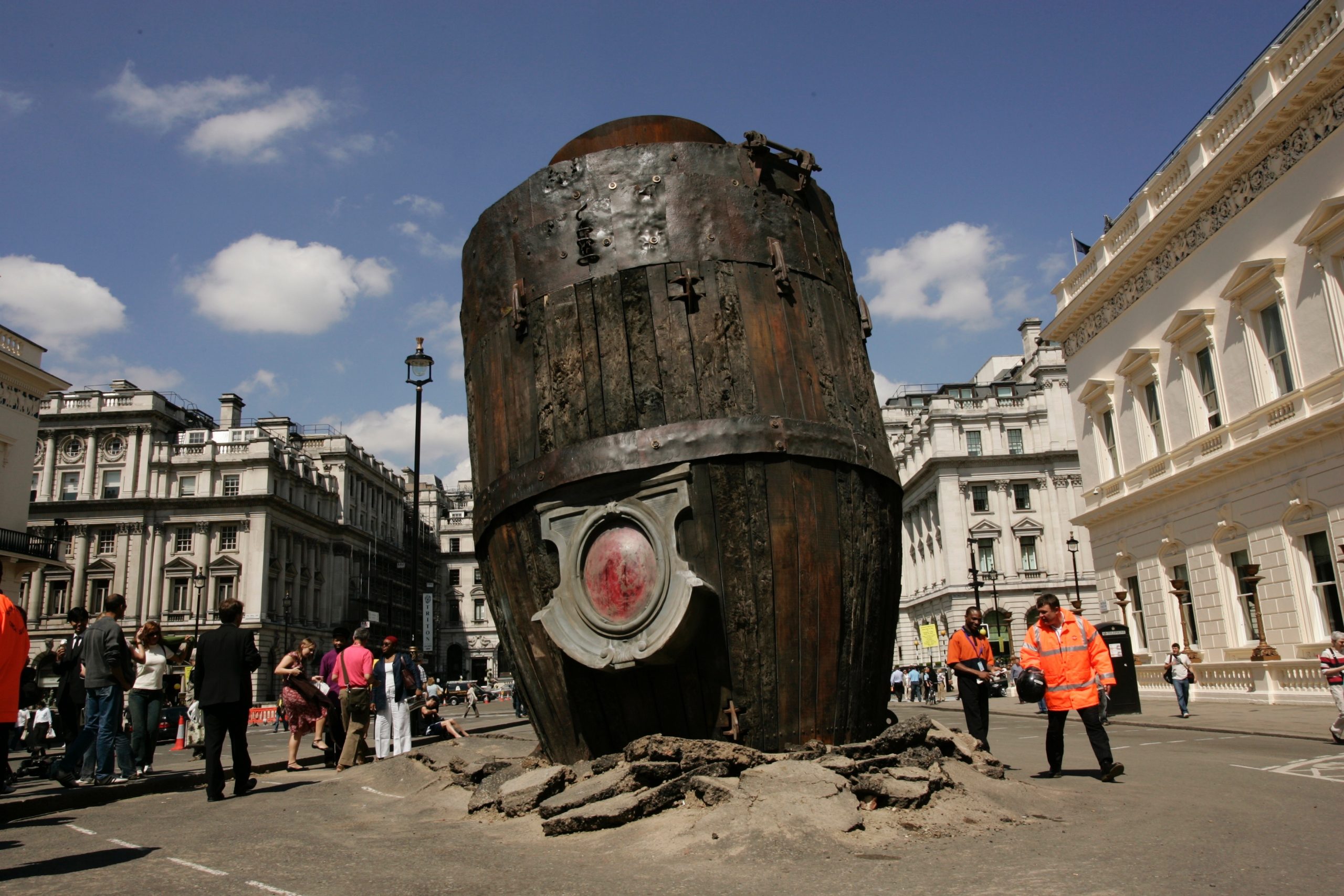 A giant wooden rocket in the middle of a road with the tarmac broken from the impact of landing