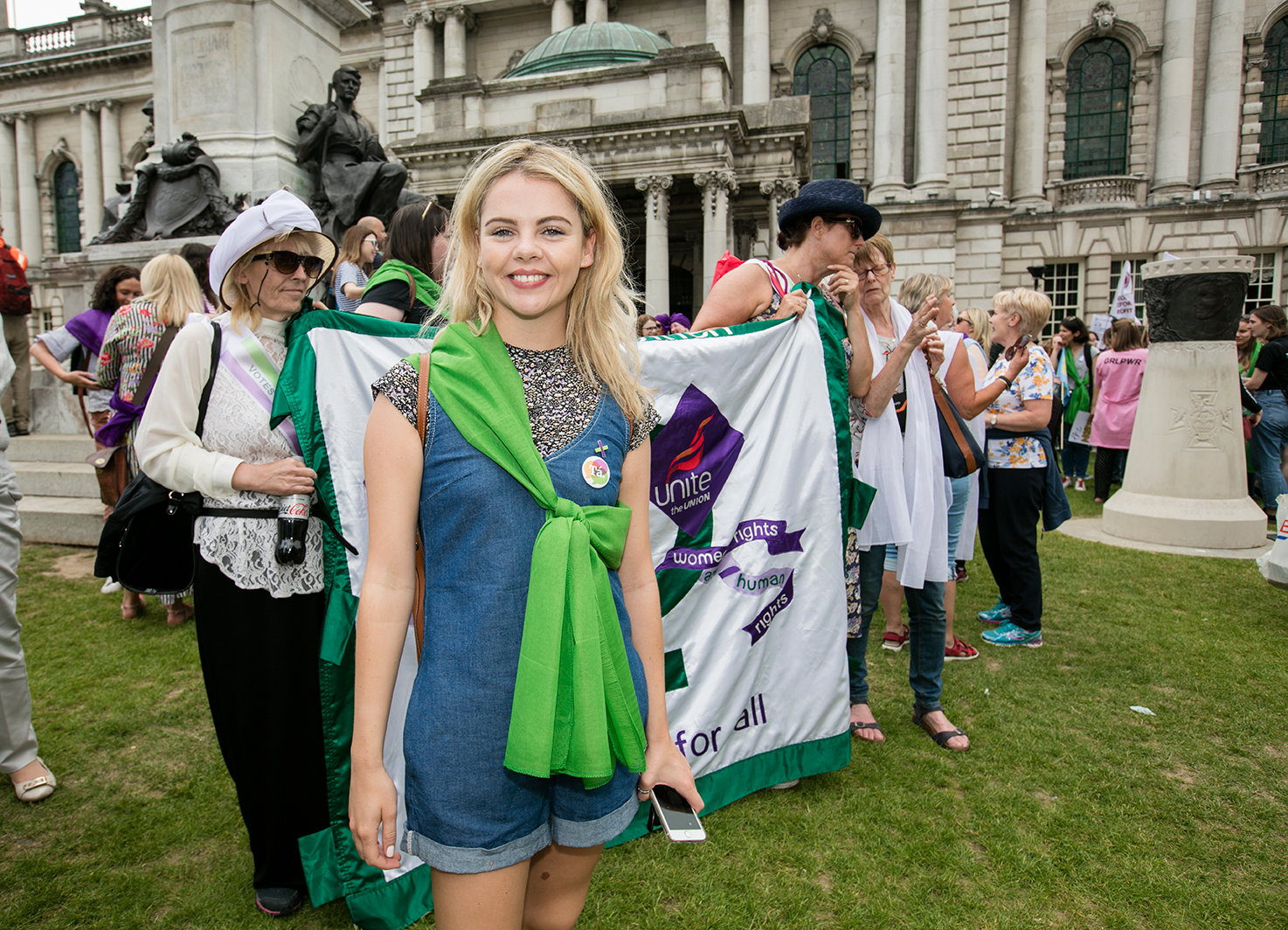 Saoirse-Monica Jackson at Processions, smiling with a green sash tied across her torso