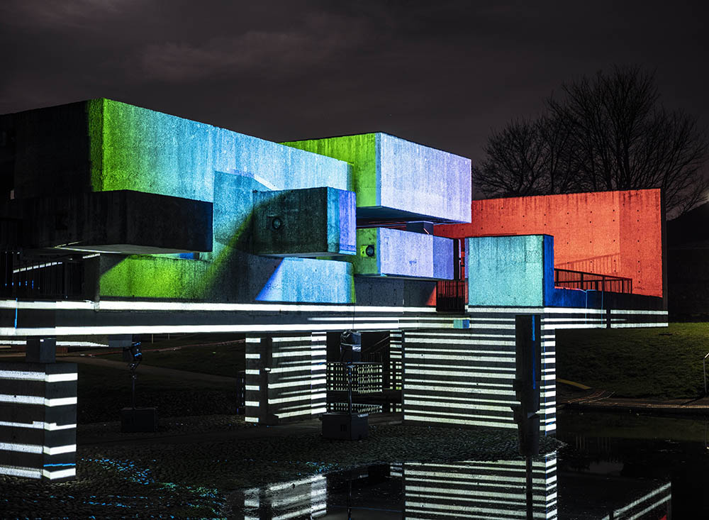 Apollo Pavilion illuminated in striped monochrome light at the bottom and block red, blue and green light on the top.