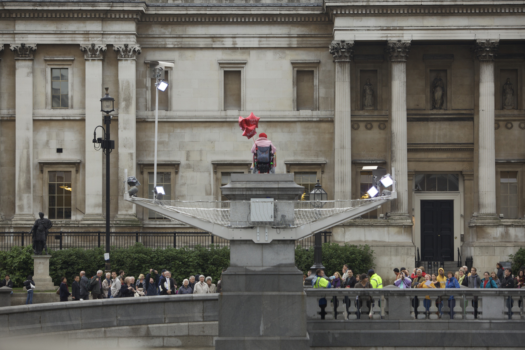 Woman with heart shaped balloon in wheel chair on the Fourth Plinth.
