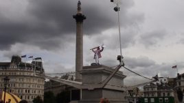 Man in top that waving a flag on top of the Fourth Plinth.