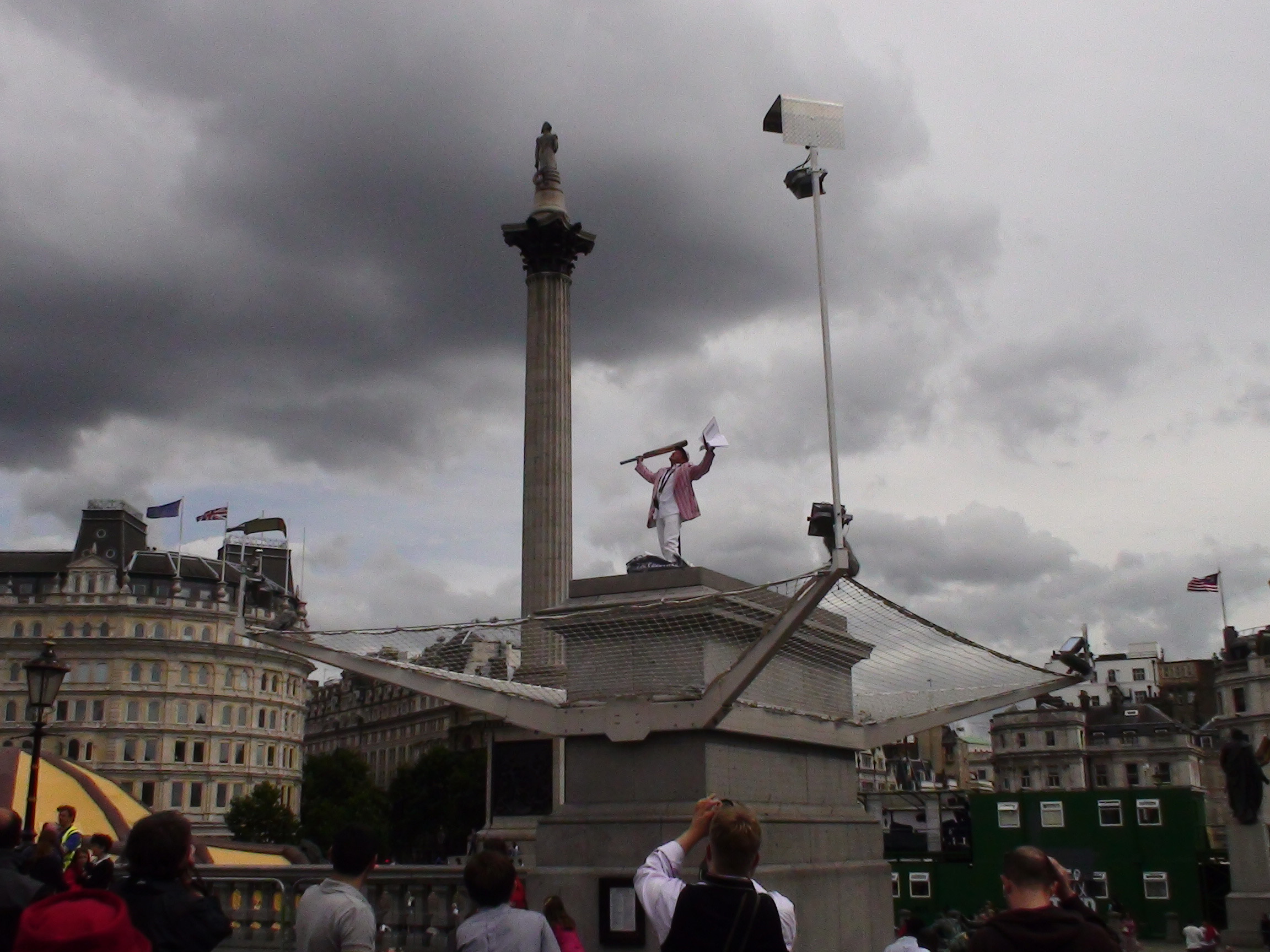 Man in top that waving a flag on top of the Fourth Plinth.