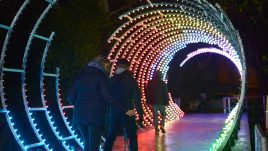 3 people watching through a rainbow light tunnel