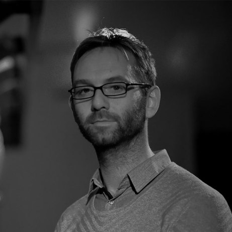 Black and white image of man wearing glasses and a polo neck