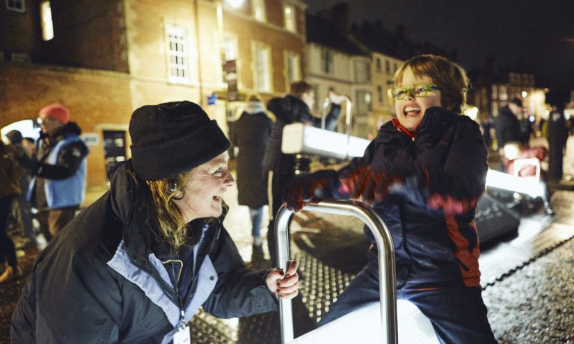 Kate Harvey interacting with illuminated see-saws, Wave-Field Variation H by CS Design and Lateral Office with a soundscape by Mitchell Akiyama at Lumiere Durham, 2019. Photo by Matthew Andrews.