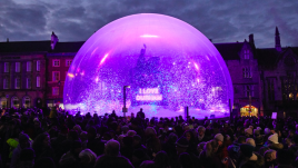 A large crowd gathered around a snow globe, in the snow globe is glitter and at the centre is a statue of a man riding a horse on a plinth with the illuminated words I LOVE DURHAM on it.