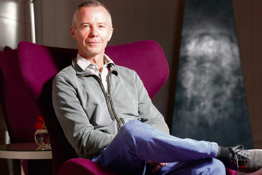 Portrait of Mel Mercier sitting on a red armchair