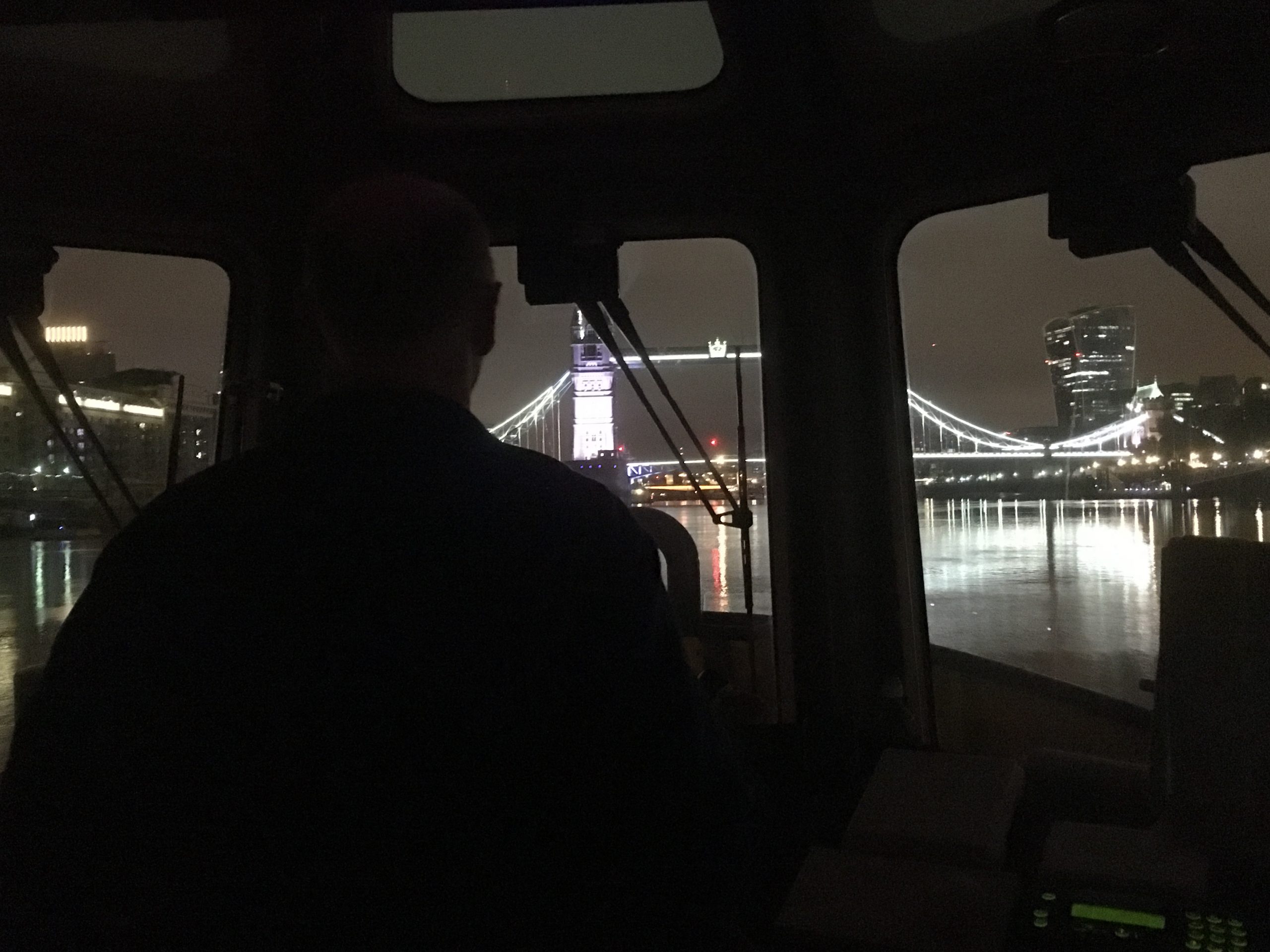 Dark view out onto the Thames from behind the wheel of a boat.