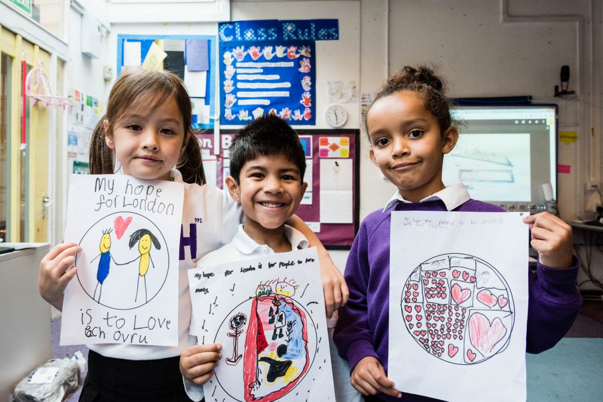 School children holding up drawings in a workshop