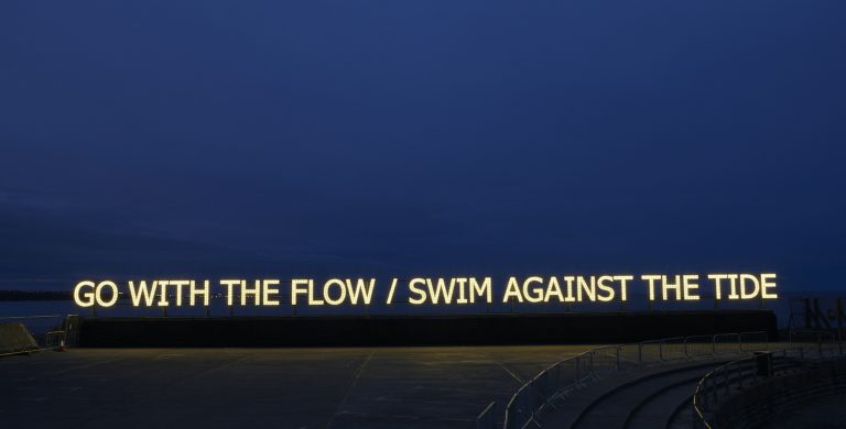 Illuminated text reads: Go with the flow / swim against the tide