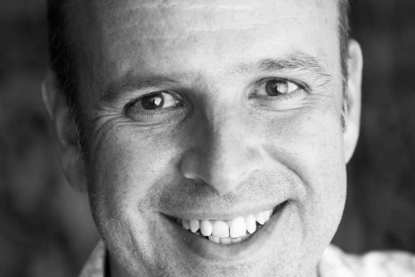 A face-on headshot of Sebastian Frost in black and white. He is wearing a flowery shirt