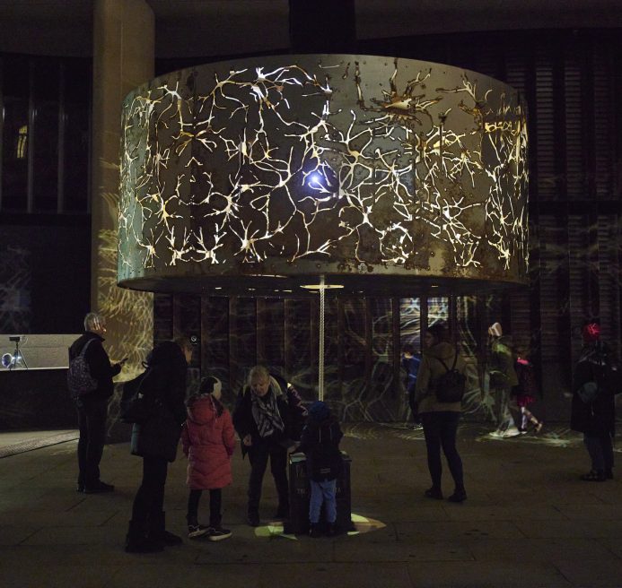 a large circular lampshade like structure with nerves reflecting out on the walls around it