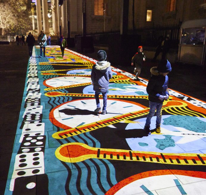 People walking across an animated light projection in the St Pauls courtyard