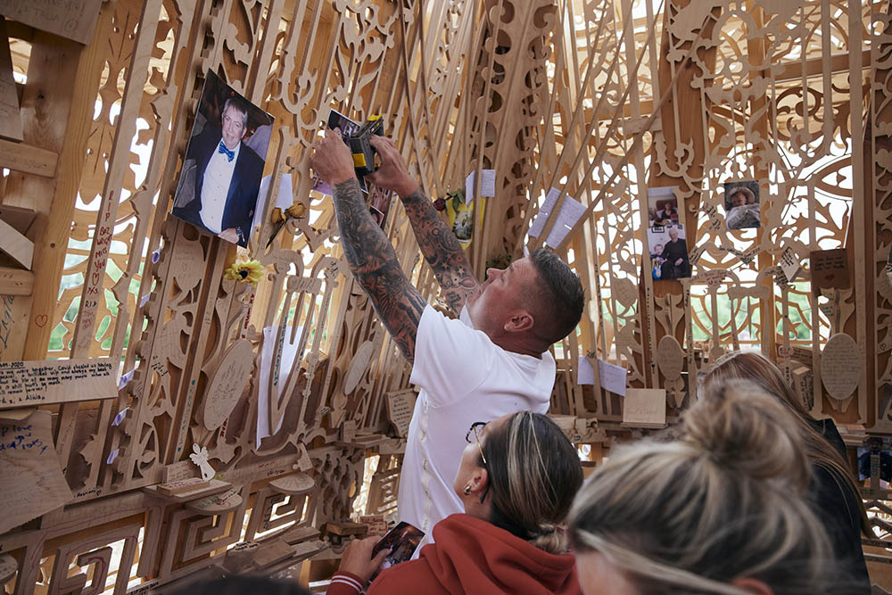 Visitor pinning up a photograph on the wall inside Sanctuary