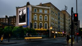 Photo of art by Anna Martynenko on a billboard; Black and white photo of twin brothers. One face the camera and the other faces away