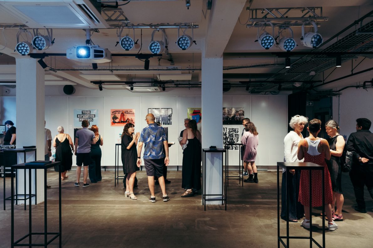 Wide shot of people mingling with artworks at The Gallery launch event.