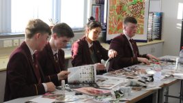 A photo from a schools workshop in Northern Ireland for Season 2 of The Gallery. A group of young people sit in a classroom with piles of magazines on their work stations. They are creating collages in repsonse to the theme 