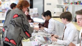A photo from a schools workshop in Northern Ireland for Season 2 of The Gallery. A group of young people sit in a classroom with piles of magazines on their work stations. They are creating collages in repsonse to the theme 