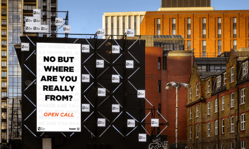 A billboard displays the words: NO BUT WHERE ARE YOU REALLY FROM? OPEN CALL