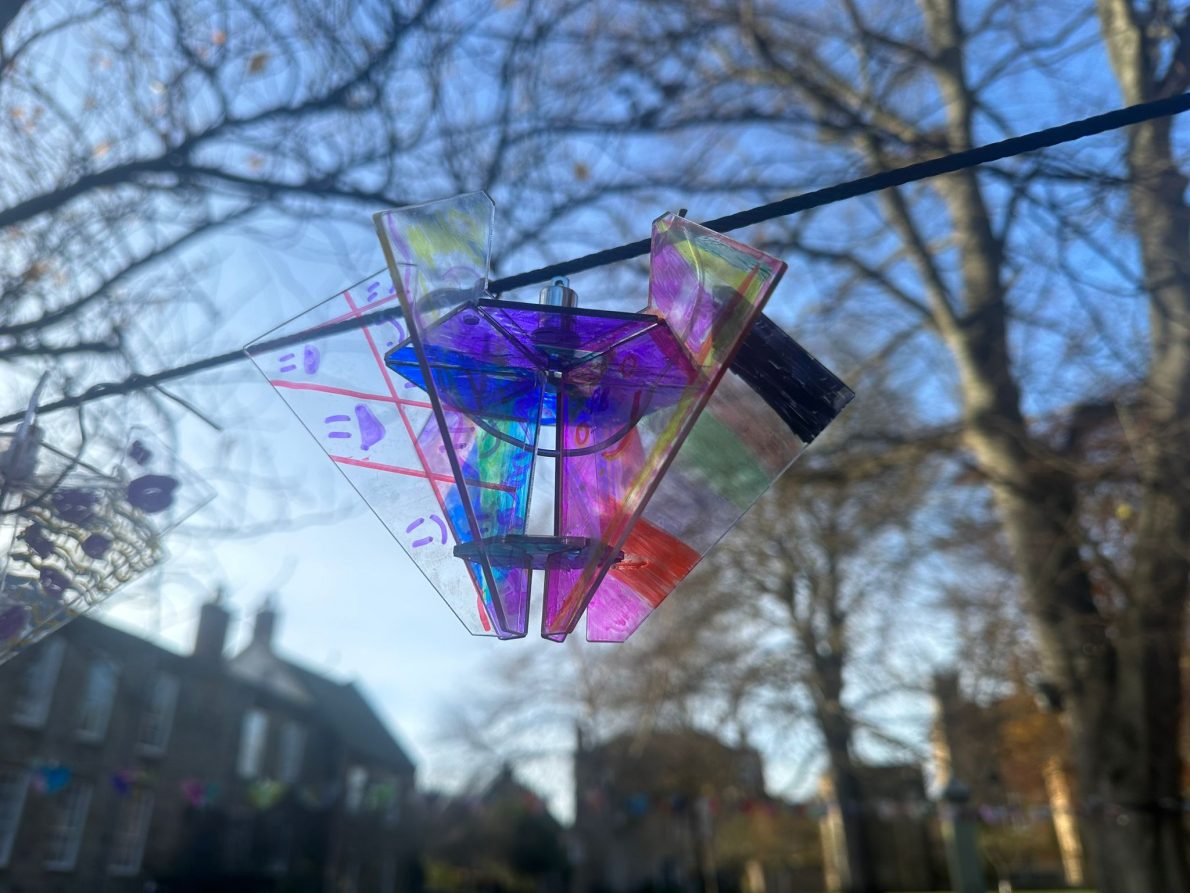 Close-up of mini diamond artwork hanging from a tree branch.