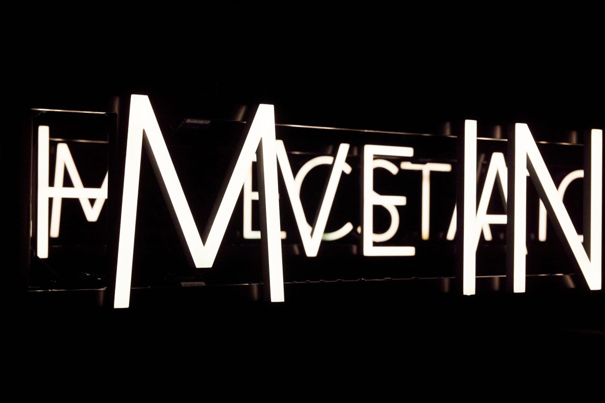 A neon text installation close-up of overlaying letters. Seen at night.