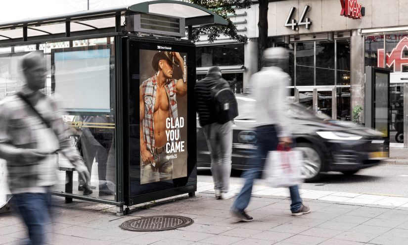 A billboard showing a sexy cowboy with an open vest revealing his muscular torso. He cocks his cowboy hat at the camera. Text reads 